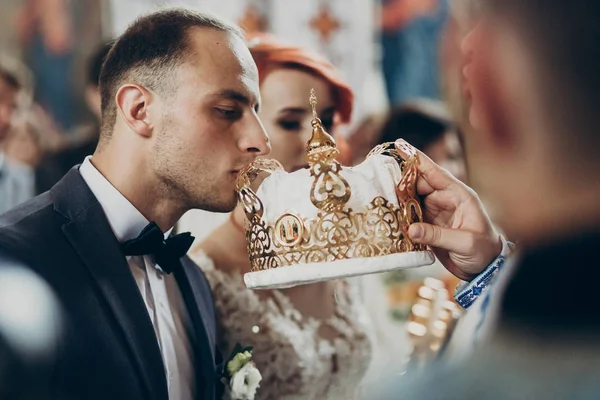 Braut und Bräutigam küssen Kronen — Stockfoto