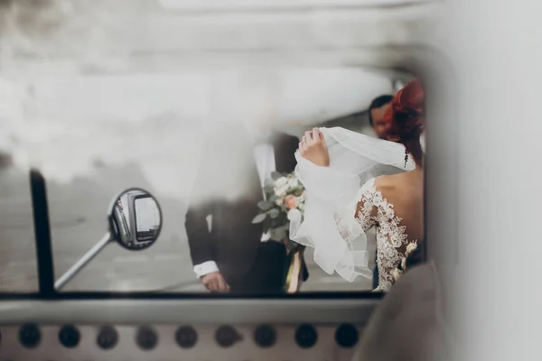 Bruid met sluier en bruidegom met boeket — Stockfoto