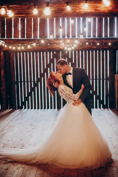 Newlyweds kissing in rustic barn — Stock Photo, Image