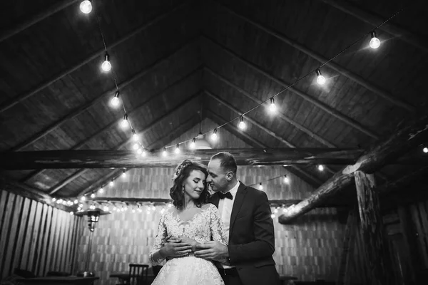 Recém-casados abraçando sob luzes retro — Fotografia de Stock