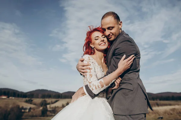 Recém-casados sorrindo abraçando nas montanhas — Fotografia de Stock