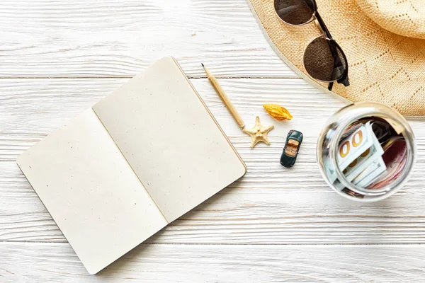 Notebook com lápis, dinheiro, óculos de sol e chapéu — Fotografia de Stock