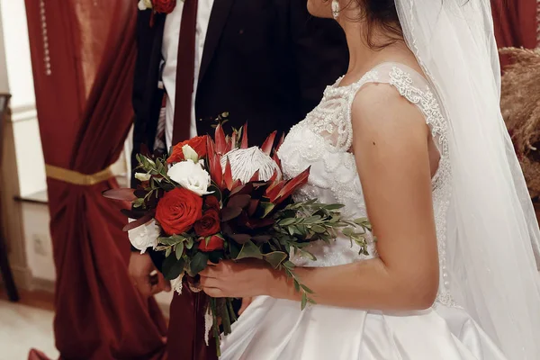 Recém-casados com buquê no arco — Fotografia de Stock