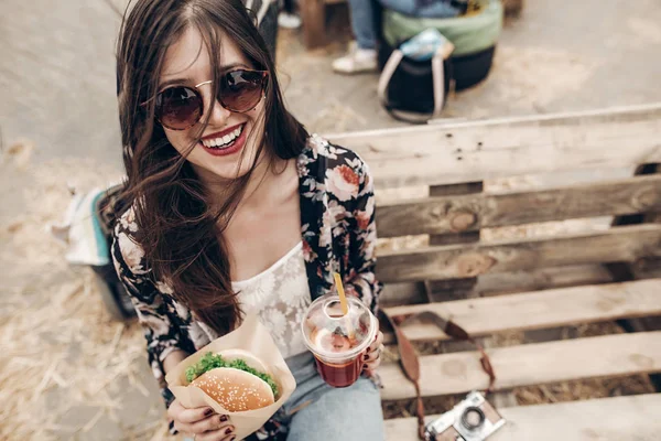 Chica riendo sosteniendo hamburguesa y limonada — Foto de Stock