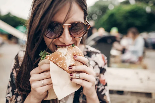 Дівчина в сонцезахисних окулярах кусає гамбургер — стокове фото
