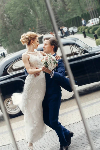Abraço de noiva com noivo perto do carro — Fotografia de Stock