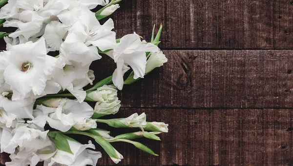 Белые гладиолусы на деревянном фоне — стоковое фото