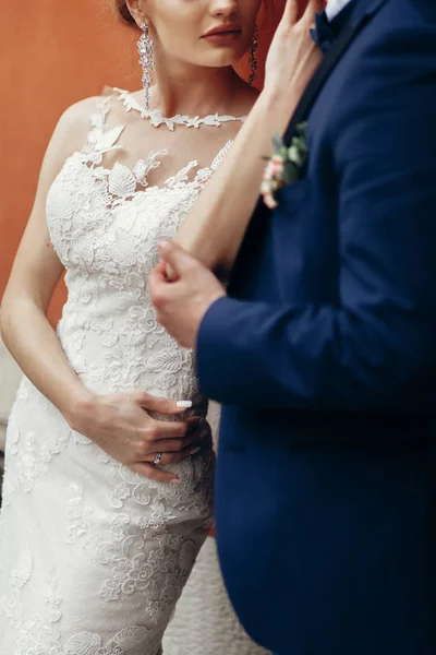 Newlywed couple posing near wall — Stock Photo, Image