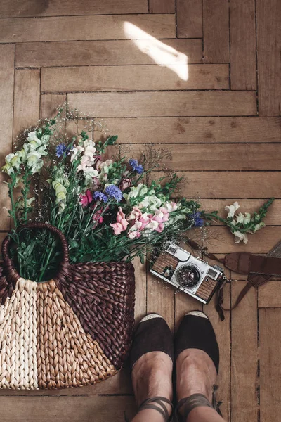 Полевые цветы в сумке, фотоаппарат и женские ноги — стоковое фото