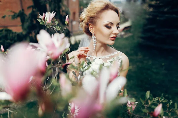 Sposa posa vicino fiori magnolia — Foto Stock