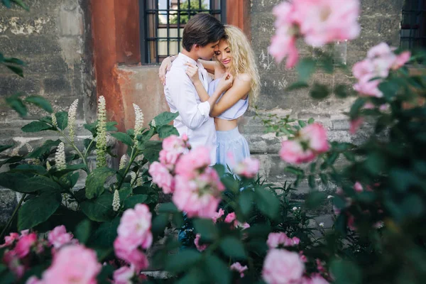 Casal perto de flores rosa — Fotografia de Stock