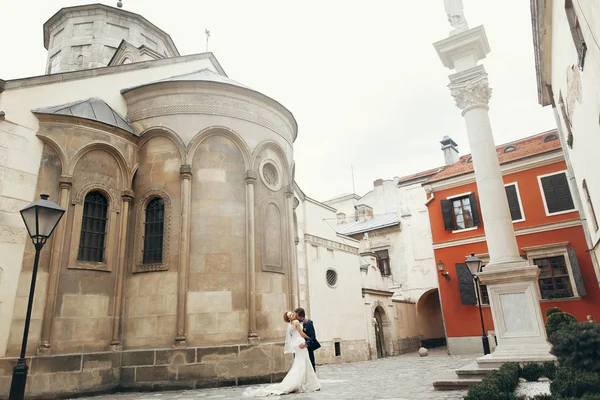 Casal recém-casado posando perto de edifício antigo — Fotografia de Stock