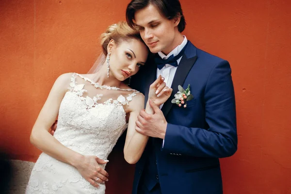 Newlywed couple posing near wall — Stock Photo, Image