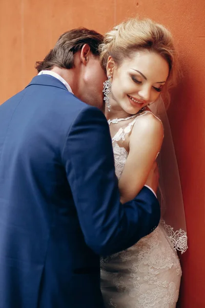 Casal recém-casado posando perto da parede — Fotografia de Stock