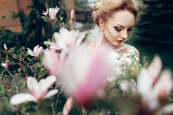 Sposa posa vicino fiori magnolia — Foto Stock