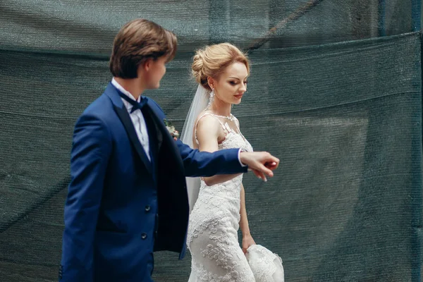 Nowożeńcy, trzymając się za ręce, chodzenie na zewnątrz — Zdjęcie stockowe