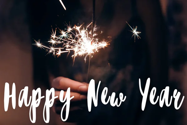 新年あけましておめでとうございますテキストと女性の書き込みのベンガル ライトは暗闇の中で手します — ストック写真