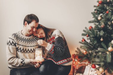 gülüyor ve Noel ağacı oturan fener ışık tutan eğleniyor genç mutlu çift