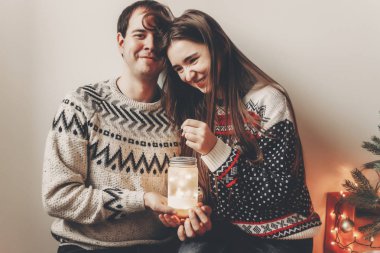 gülüyor ve Noel ağacı oturan fener ışık tutan eğleniyor genç mutlu çift