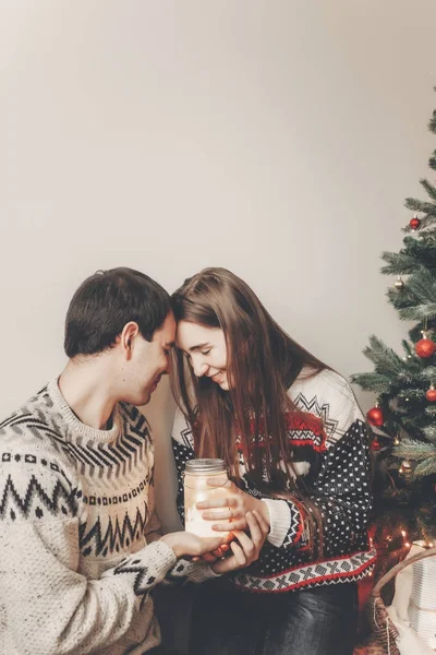 Ung Familie Med Lanterne Smilende Sidder Ved Julepyntet Træ - Stock-foto