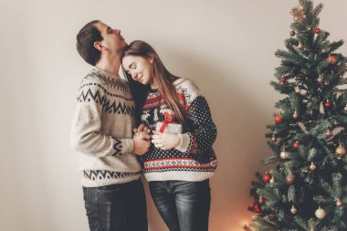 Noel yakın hediye kutusu ayakta tutan genç mutlu çift süslenen ağacı