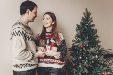 Noel yakın hediye kutusu ayakta tutan genç mutlu çift süslenen ağacı