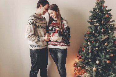 Noel yakın hediye kutusu ayakta tutan genç mutlu çift süslenen ağacı