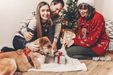 mutlu Noeller ve mutlu yeni yıl kavramı. şık hipster aile içinde köpek ve Hediyelik Noel ağacı ışıkları ile şenlikli kazak. İyi Bayramlar. Mevsimlik selamlar