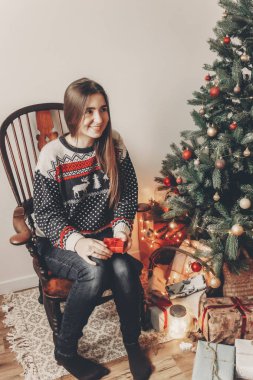 Festival kazak Noel hediye tutarak ağacın altında oturup şık hipster kadında