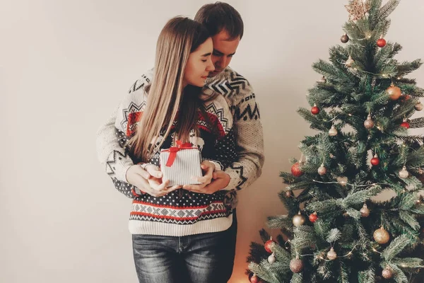 セーター赤弓立ってクリスマス ツリーとギフト ボックスを抱きしめるとの幸せカップル — ストック写真