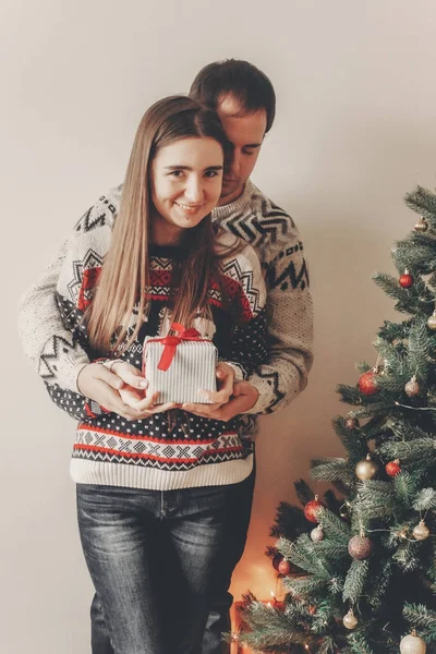 セーター赤弓立ってクリスマス ツリーとギフト ボックスを抱きしめるとの幸せカップル — ストック写真