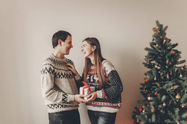 クリスマス ツリーの近くに立って 笑っている幸せカップル交換プレゼントします — ストック写真