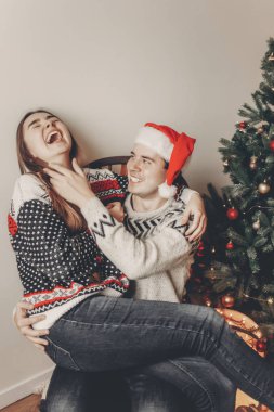 mutlu genç adam Noel ağacın altında oturup onun kız sarılma 