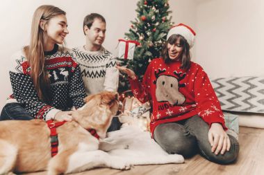 hediye ile eğlenmek ve ışık ile Noel ağacı köpeğe oynamaktan mutlu aile