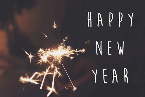 新年あけましておめでとうございますテキスト記号、燃える線香花火花火ベンガル光を持っている手. — ストック写真