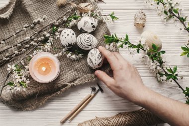 Modern Paskalya yortusu yumurta üstten görünüm rustik arka planda tutan el. tatil, Paskalya kutlamaları için hazırlık. şık boyalı yumurta... Aile gelenekleri. düz lay