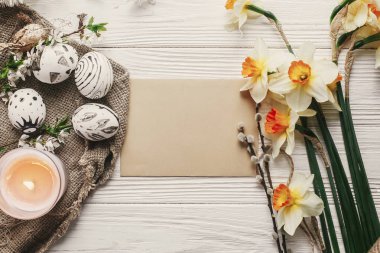 Mutlu Paskalya tebrik kartı mock-up. taze bahar çiçekleri ve Nergis Tepe manzaralı rustik arka plan üzerinde modern Paskalya yumurta. şık boyalı yumurta. Paskalya düz yatıyordu