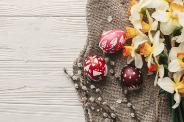 Modern Paskalya düz yatıyordu. bahar çiçekleri nergis rustik Beyaz ahşap arka plan en iyi görünümü ile şık renkli Paskalya yumurtaları. metin için yer. şık boyalı yumurta. tebrik kartı