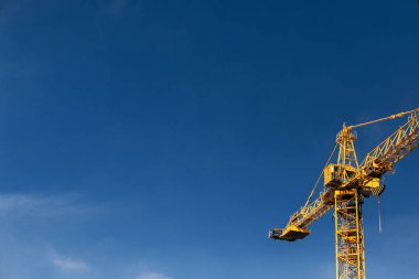 İnşaat vinç kule mavi gökyüzü arka plan üzerinde. Vinç ve bina inşaat sitede çalışma ilerleme. Sarı kaldırma musluk. Metin için yer. İnşaat kavramı