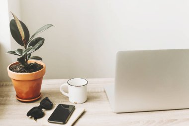 Ahşap Masaüstü telefon, defter, kahve fincanı, gözlük ve şık modern oda tesisi ile laptop. 