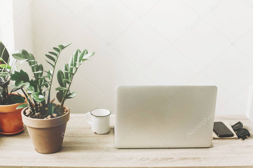 Freelance concept. Desktop with laptop, phone, notebook, coffee cup and plants