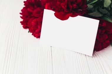 çiçek tebrik kartı kavramı, alay etmek yukarıya. Kraft kağıt Beyaz ahşap rustik arka planda güzel kırmızı peonies buket. metin için yer. düğün davetiyesi