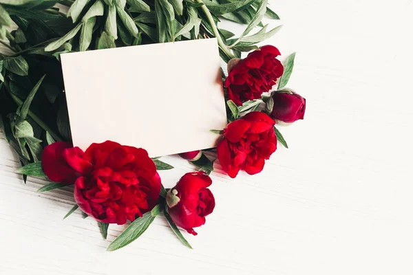 花のグリーティング カードのコンセプト モックアップ 白い木製の素朴な背景のペーパー クラフトと美しい赤いシャクヤク ブーケ テキストのためのスペース 結婚式招待状 — ストック写真