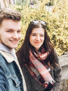 eğlenceli ve çekici selfie günbatımı güneş ışığı Bahar park içinde çiçek açan ve rahatlatıcı sarı çiçeklere sahip güzel hippi çift