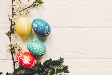 şık Paskalya yumurtaları ve ahşap zemin düz beyaz çiçekler yatıyordu. modern yumurta doğal boyalı. metin için yer. Mutlu Paskalya tebrik