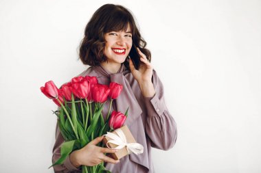 Evet ve pembe laleler ve hediye kutusu ile kurdele beyaz arka plan üzerinde tutan mutlu şık kız. 