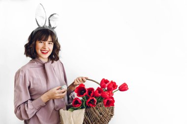 Paskalya AVI kavramı. sepet laleler ve Paskalya yumurtası ayakta beyaz arka planda tutan güzel şık kız