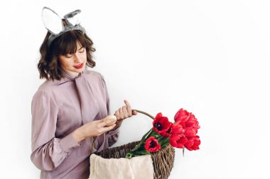 Paskalya AVI kavramı. sepet laleler ve Paskalya yumurtası ayakta beyaz arka planda tutan güzel şık kız