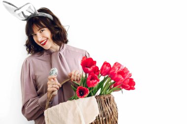 Paskalya AVI kavramı. sepet laleler ve Paskalya yumurtası ayakta beyaz arka planda tutan güzel şık kız