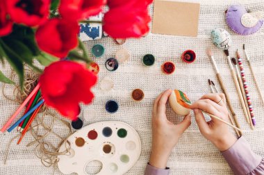 Holding ve Paskalya yumurtaları boya ve Lale ile rustik tabloda resim eller. mutlu kız Paskalya kutlamaları ve hunt için hazırlanıyor. Mutlu Paskalya kavramı. düz lay